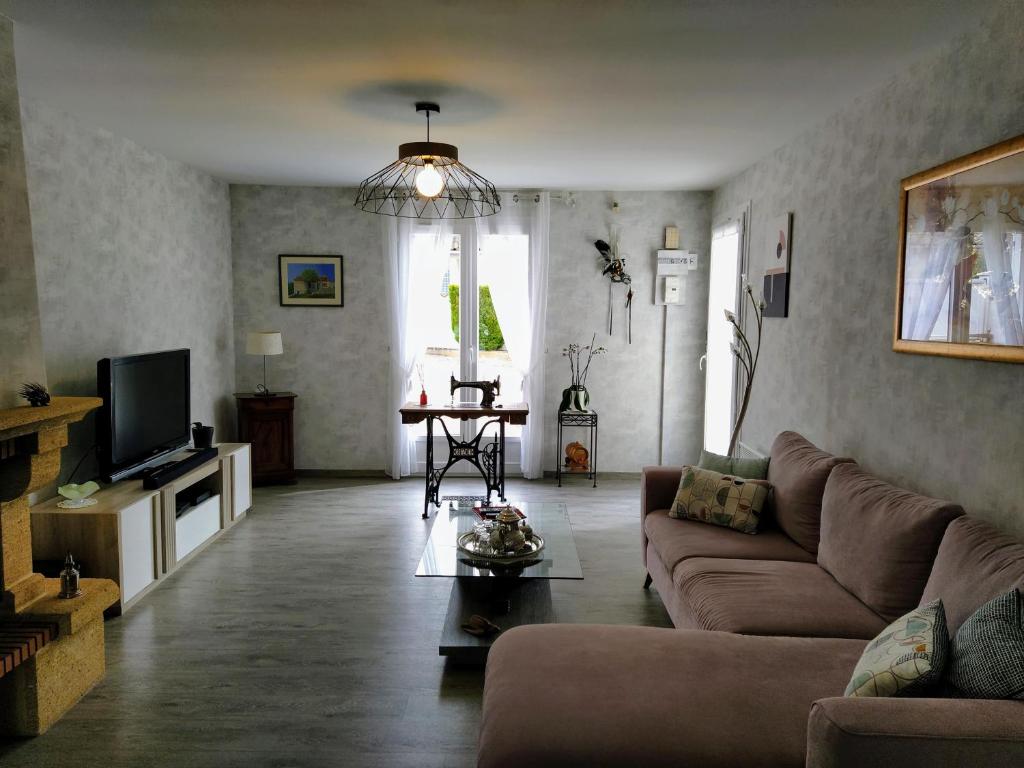 uma sala de estar com um sofá e uma televisão em Maison plain pied avec jardin, terrasse et veranda em Cognac
