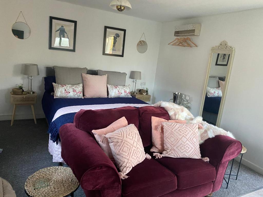 um quarto com uma cama e um sofá com almofadas em The Wee house at the cottage em Annan