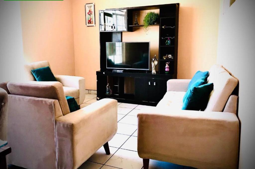 a living room with two chairs and a flat screen tv at House explorer in Cusco