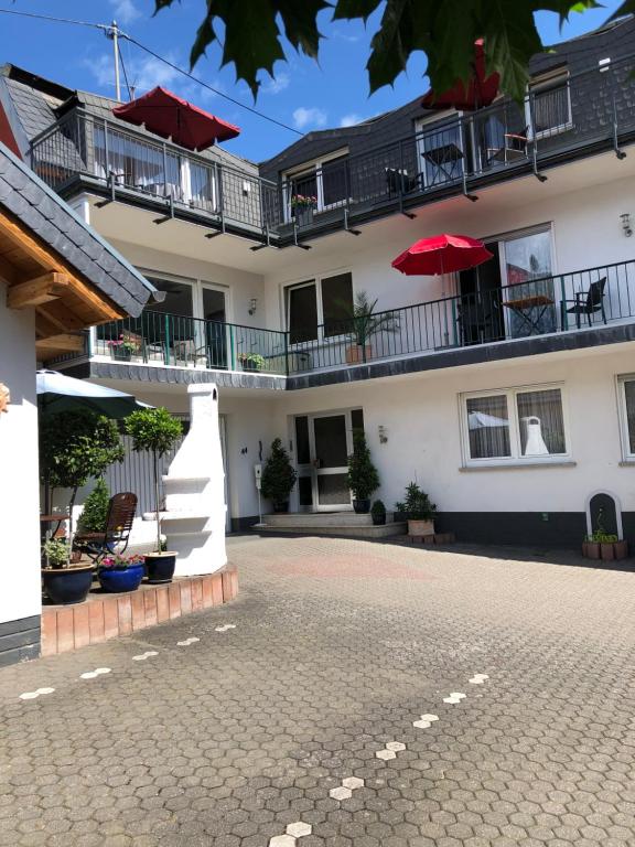 a courtyard of a building with a red umbrella at Wein und Gästehaus Hüls in Kröv