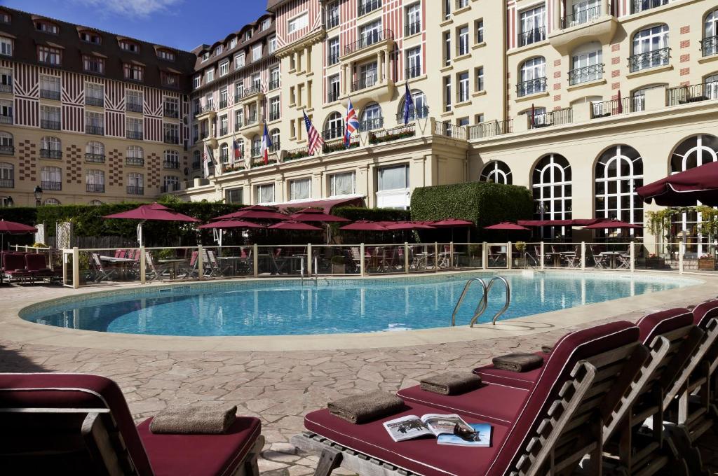 une grande piscine en face d'un bâtiment dans l'établissement Hôtel Barrière Le Royal Deauville, à Deauville