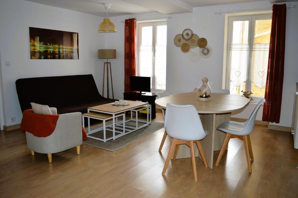 ein Wohnzimmer mit einem Sofa, einem Tisch und Stühlen in der Unterkunft L'escapade - Logement les pieds dans l'eau à Luc in Luc-sur-Mer