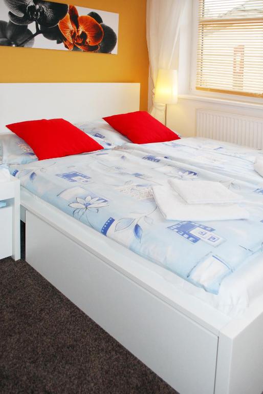 duże białe łóżko z czerwonymi poduszkami w obiekcie Apartmány Rokytka u sjezdovky w Rokitnicach nad Izerą