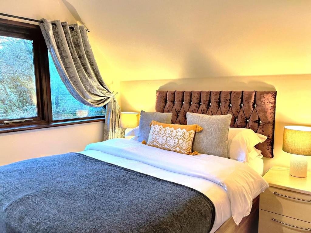 BlueBell 16-Hot Tub-Woodland Lodges-Pembrokeshire في كرمرثن: غرفة نوم بسرير كبير ونافذة