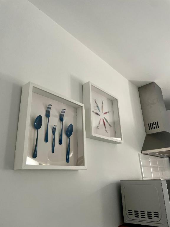 two pictures of utensils hanging on a kitchen wall at Marujita Vilanova, alojamiento singular in Villanueva de Arosa