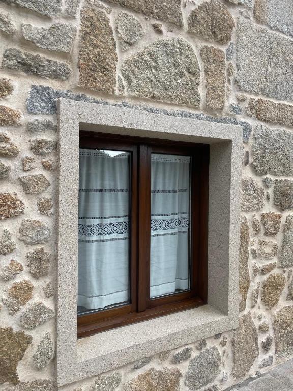 a window in a stone building with curtains at Marujita Vilanova, alojamiento singular in Villanueva de Arosa