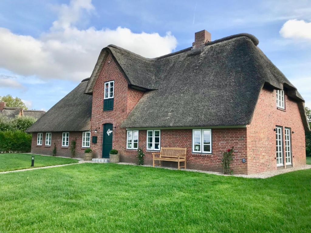 a red brick house with a thatched roof at Green Wening in Borgsum