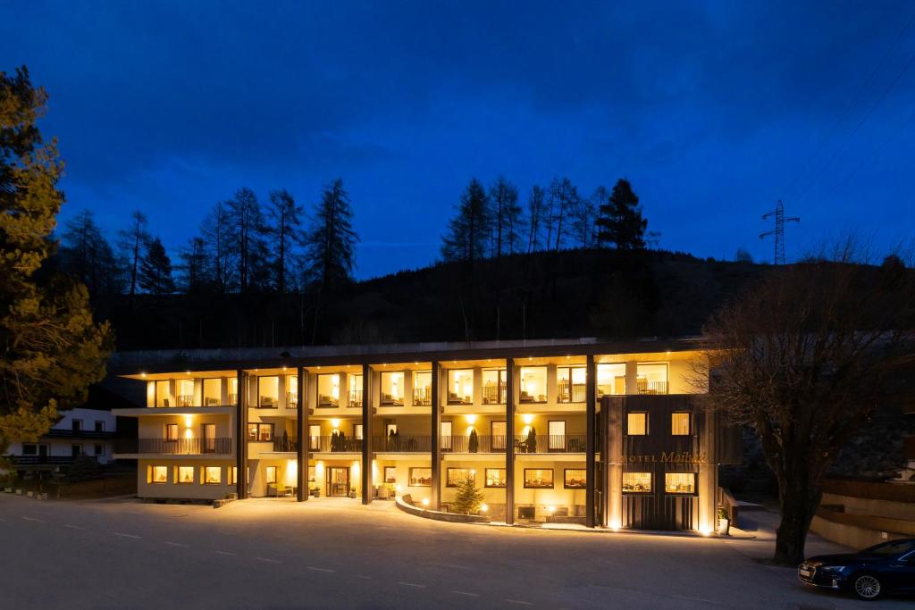 um grande edifício com luzes acesas à noite em Hotel Maibad em Vipiteno