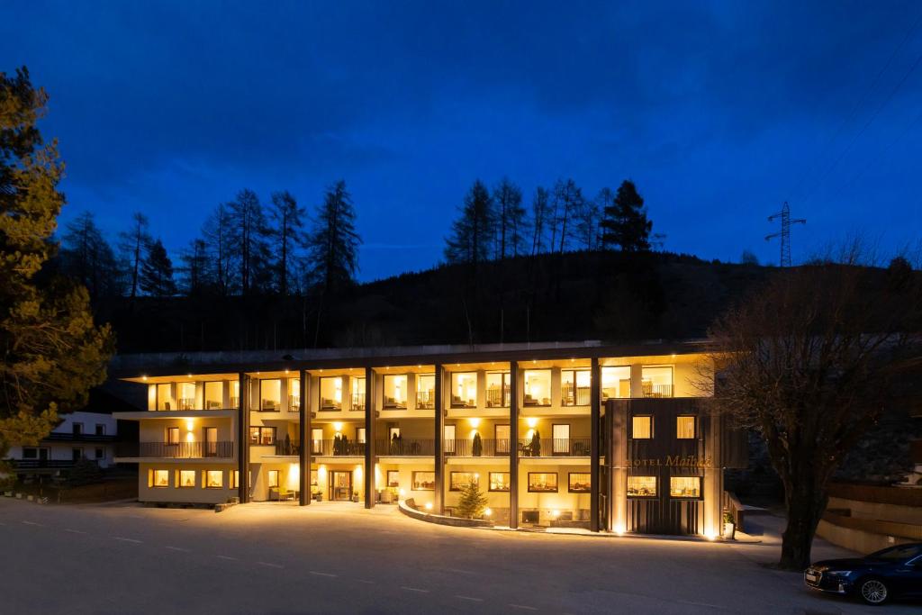een groot gebouw met 's nachts verlichting bij Hotel Maibad in Vipiteno