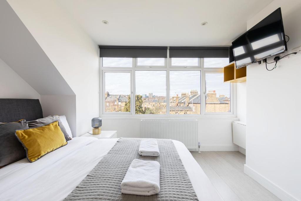 - une chambre blanche avec un grand lit et une fenêtre dans l'établissement Cozy Rooms with Shared Kitchen and Laundry Area, à Londres