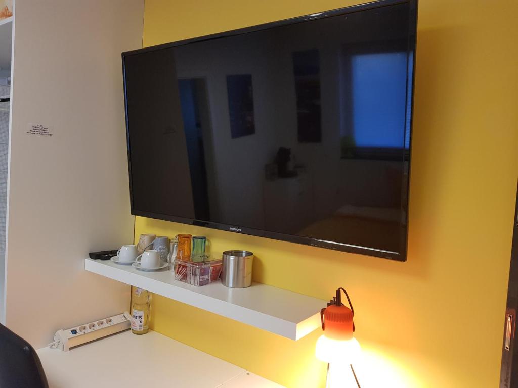 einen Flachbild-TV an einer Wand mit einem Regal in der Unterkunft Klein und fein in Erftstadt