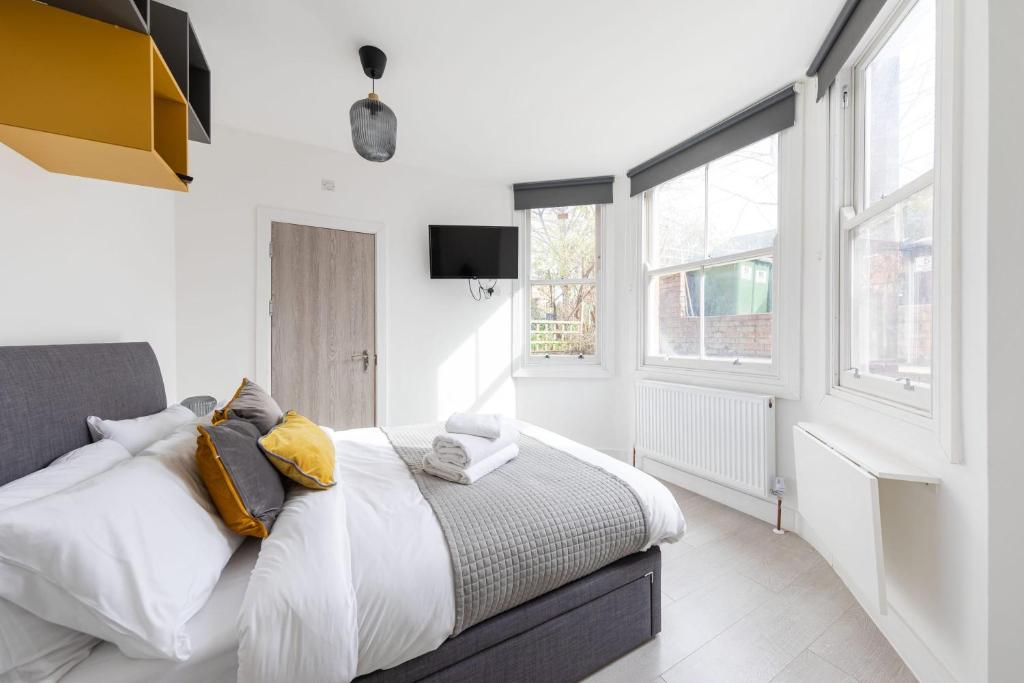 a bedroom with a bed with white walls and windows at Lovely Private Room and Shower At Anson Hotel in London