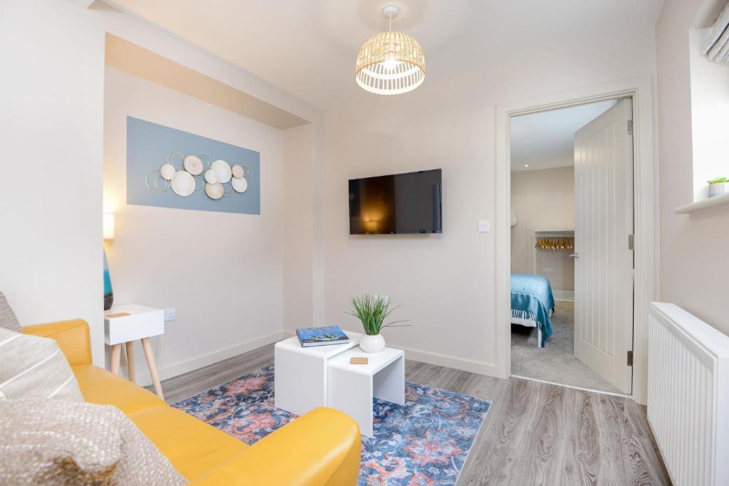uma sala de estar com um sofá amarelo e uma televisão em Apartment One - King Bed - Free Private Parking - by Ocean City Retreats em Plymouth