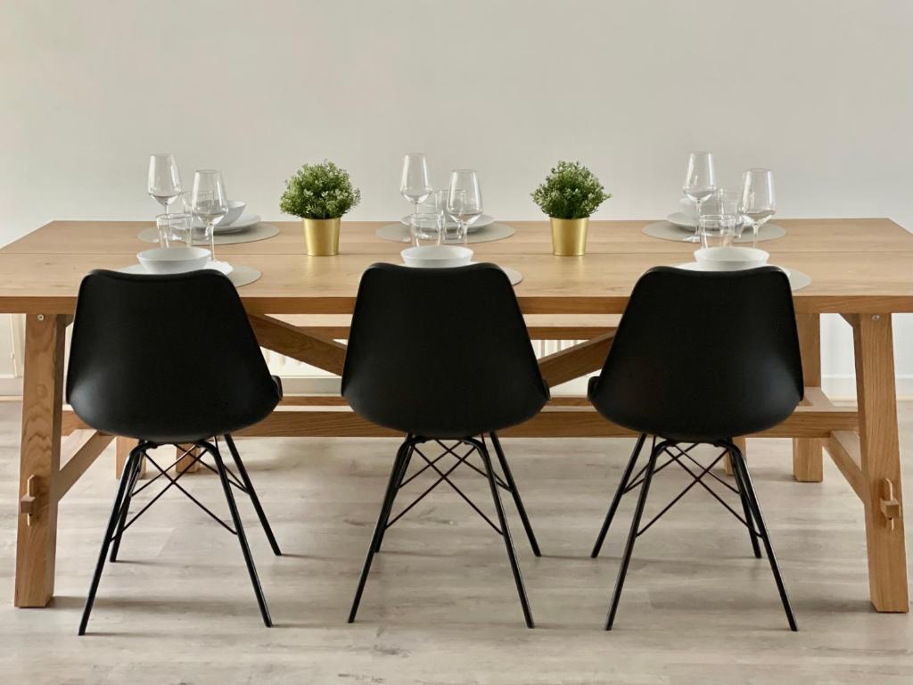 een houten tafel met drie zwarte stoelen eromheen bij Sfeer in Maaseik