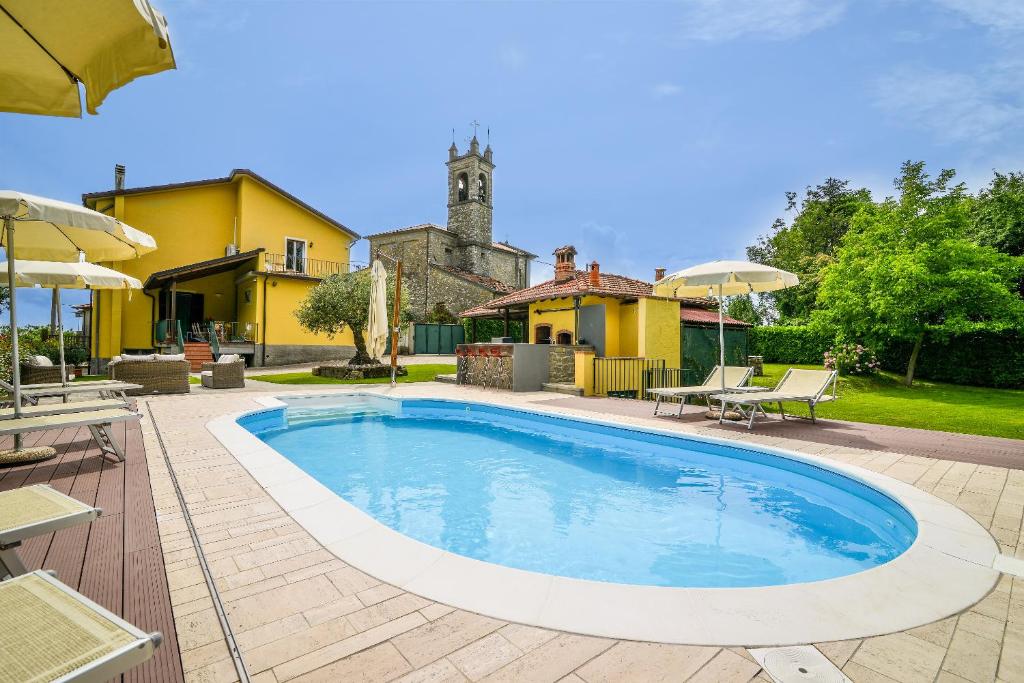 una piscina en un patio con una casa amarilla en Villa Ariola en Villafranca in Lunigiana