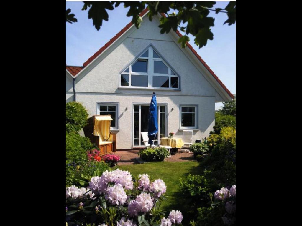 ein weißes Haus mit einem Fenster und ein paar Blumen in der Unterkunft Haus Pünktchen in Tinnum