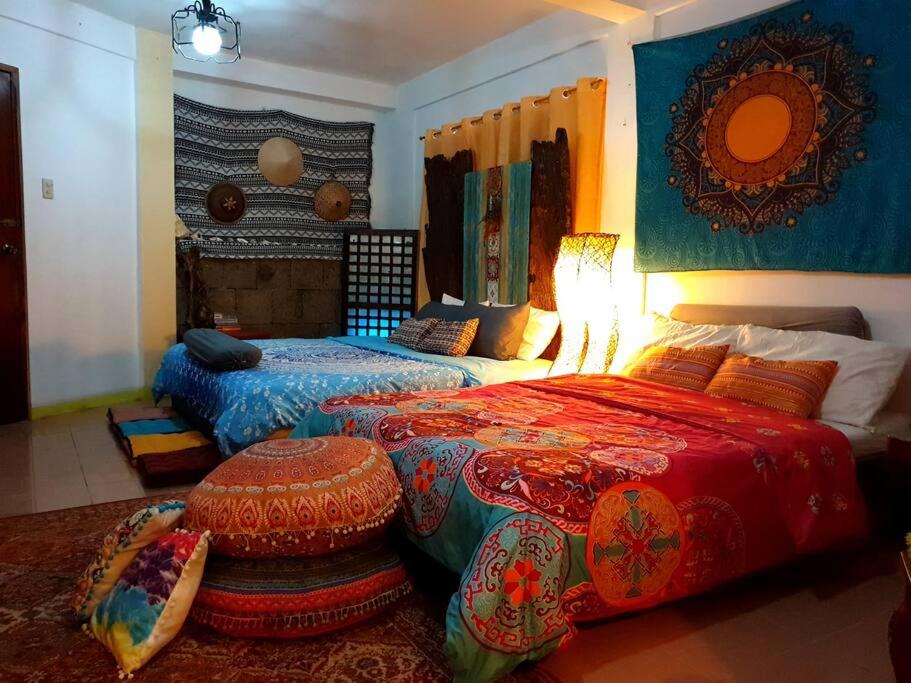 a bedroom with two beds with colorful covers and a lamp at PROMO: Shabby Chic Countryhome with Huge Garden, Jacuzzi Pool, Mini Billiards, Video Karaoke in Tagaytay