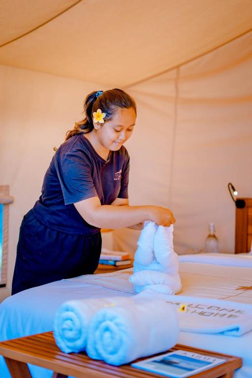 una donna in piedi in una stanza che fa asciugamani di Bali Cliff Glamping a Seraya