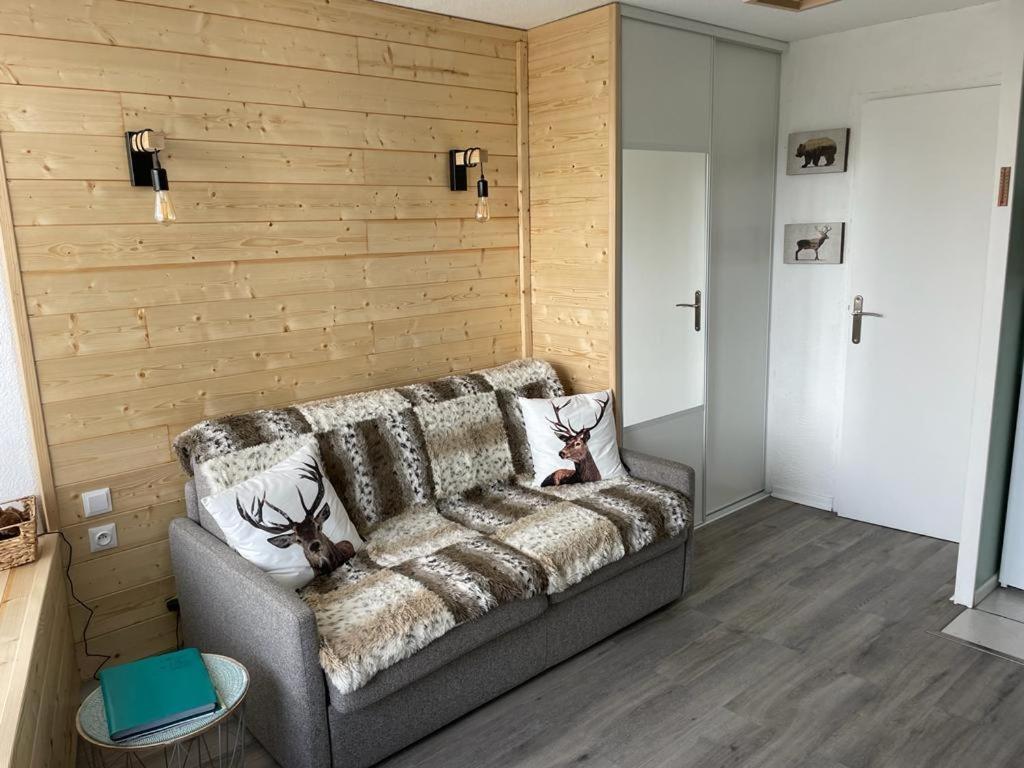 ein Sofa in einem Zimmer mit einer Holzwand in der Unterkunft RISOUL 1850 - Appart' 4 personnes ski aux pieds Agréer meublé de tourisme in Risoul