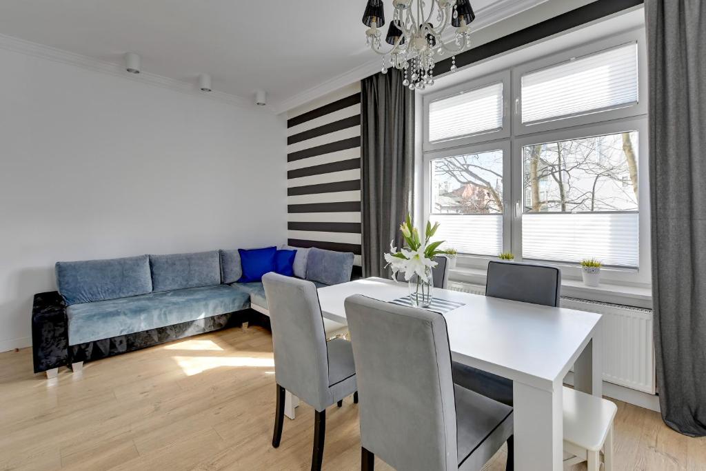 a living room with a table and a blue couch at Glamour przestronny apartament obok Monte Cassino by Grand Apartments in Sopot