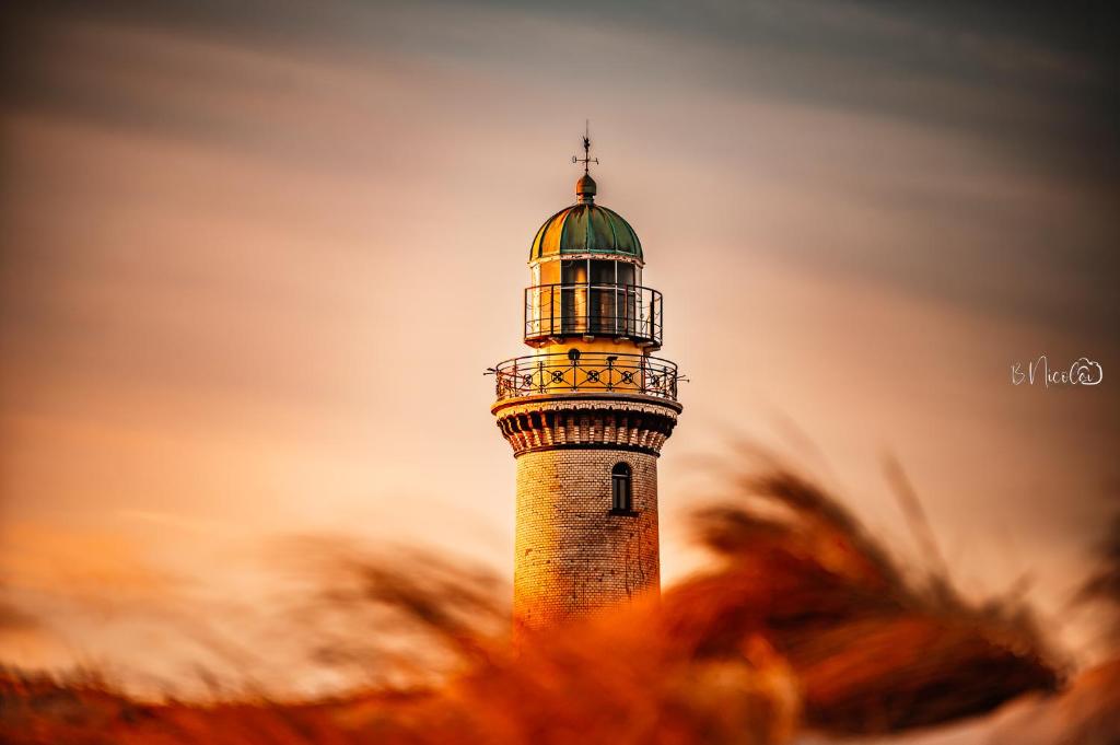 un phare au milieu d'un champ d'herbe dans l'établissement Ferienwohnung Sunset bei Warnemünde, à Rostock