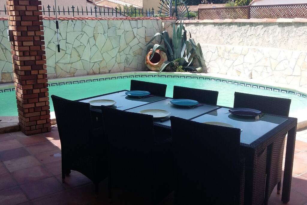 une table avec des chaises et des assiettes ainsi qu'une piscine dans l'établissement Maison avec jacuzzi, à Istres