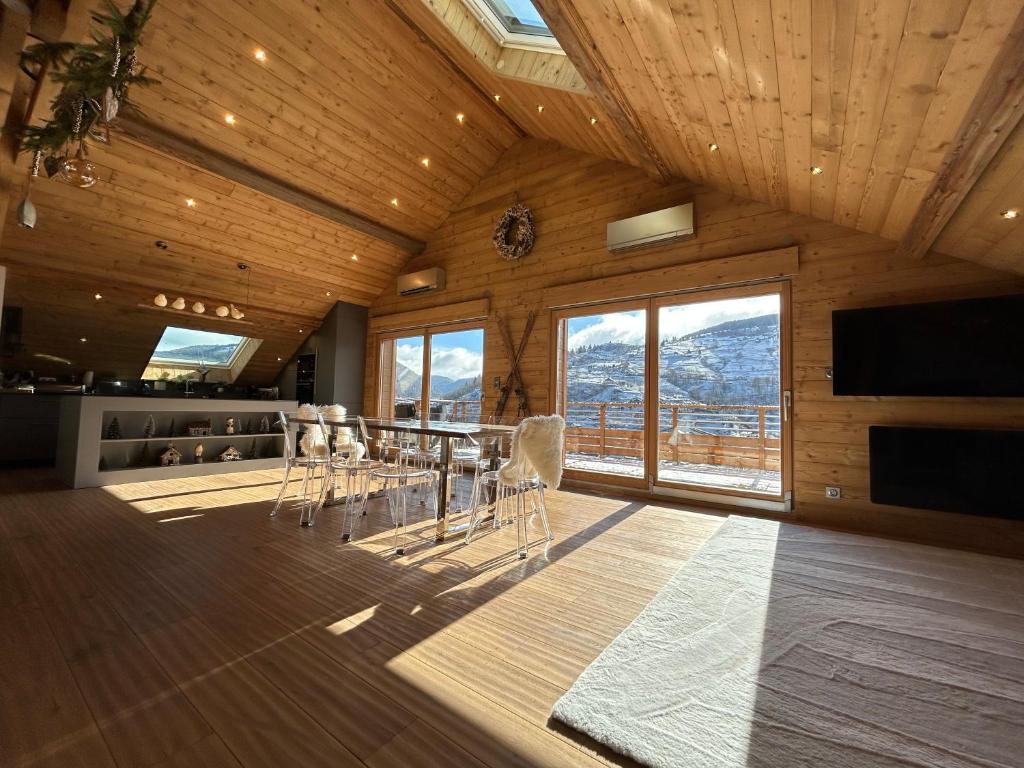 a dining room with a table and chairs and windows at Splendide appartement style chalet classé 4 étoiles, terrasse face à la montagne in La Bresse