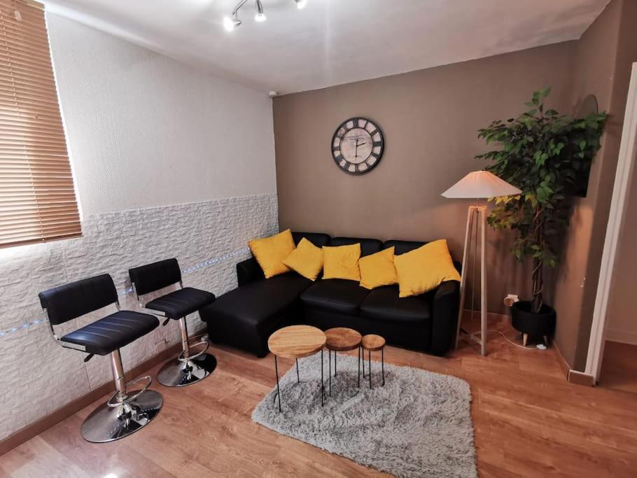 un soggiorno con divano nero e cuscini gialli di LE COSY - Appartement Pontoise Cosy Calme a Pontoise