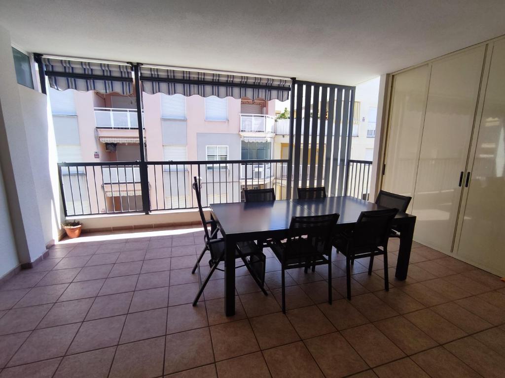 a table and chairs in a room with a balcony at Acogedor apartamento cerca de la playa in Moncófar