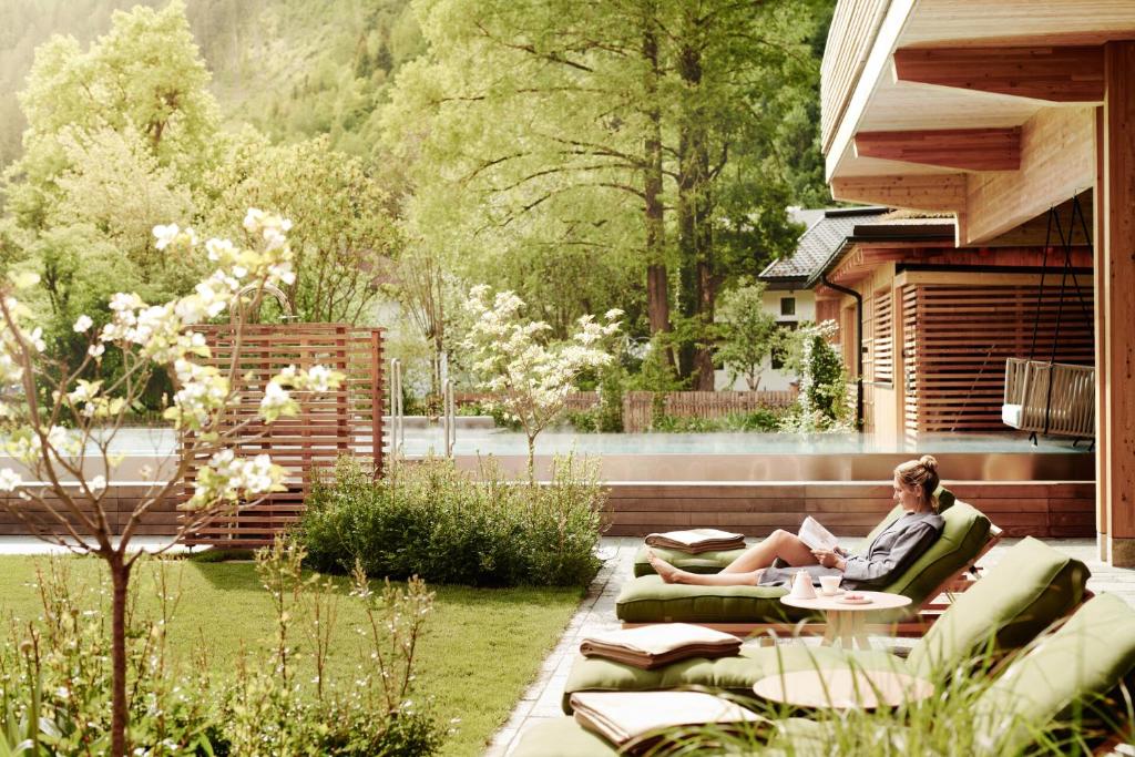 een vrouw op een bank in een tuin bij MalisGarten Green Spa Hotel in Zell am Ziller