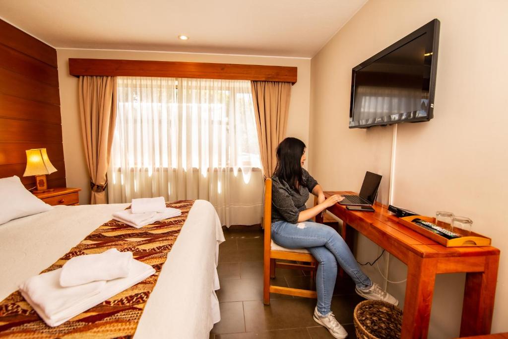 uma mulher sentada numa secretária com um portátil num quarto de hotel em Vientos del Sur em Pucón