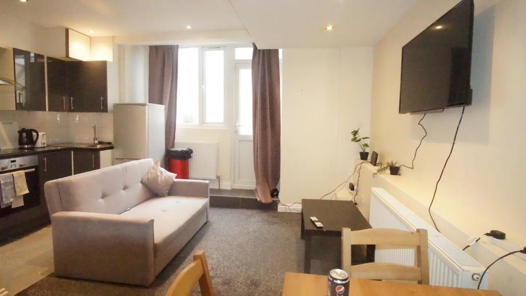 a living room with a couch and a kitchen at Evergreen Apartments-Flat 7, London in London