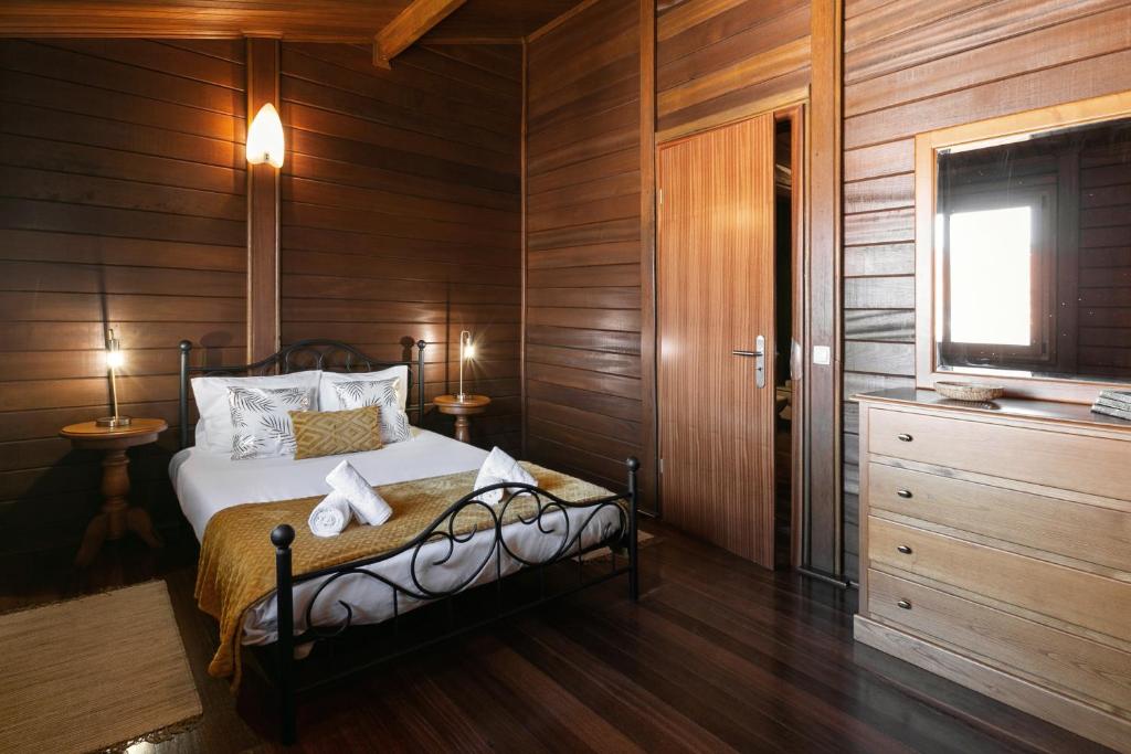 una camera da letto con un letto, pareti in legno e una TV di Unique Wooden Cottage a Óbidos