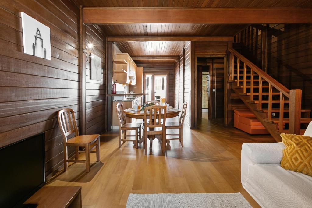 een woonkamer met een tafel en stoelen en een trap bij Stylish Rustic Villa in Vau