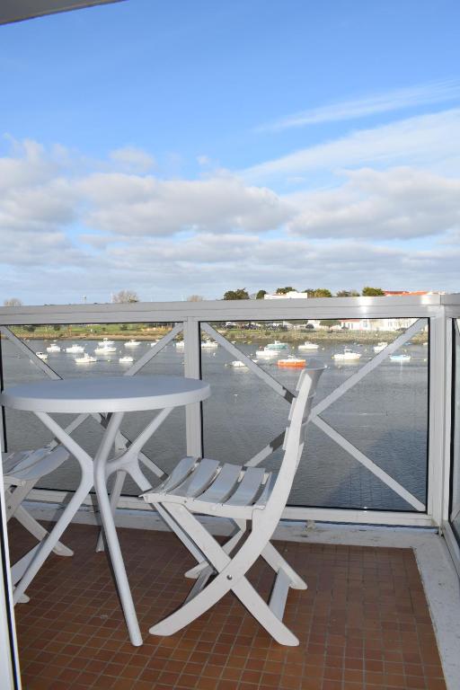 een tafel en stoelen op een balkon met uitzicht op een haven bij Côte et Vie - appartement et garage in Saint-Gilles-Croix-de-Vie
