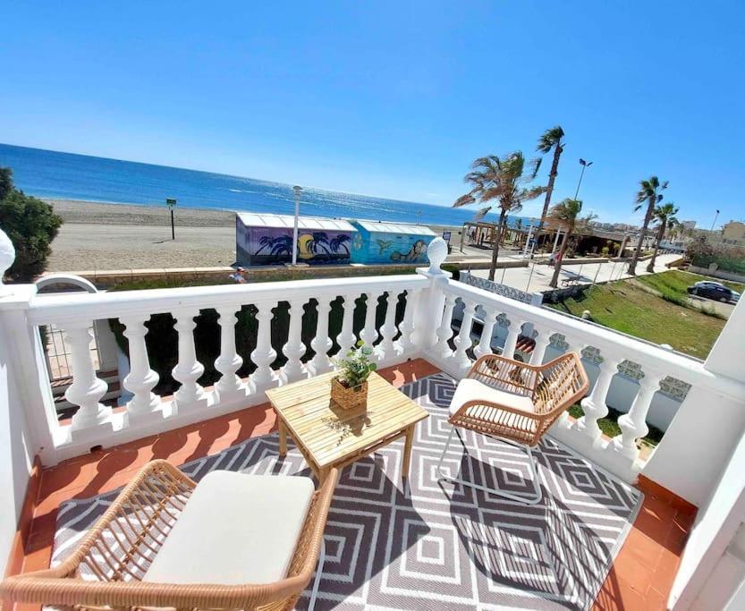 a balcony with a table and chairs and the beach at Caleta Beach House Villa Beatriz Sinese Design in Torre del Mar