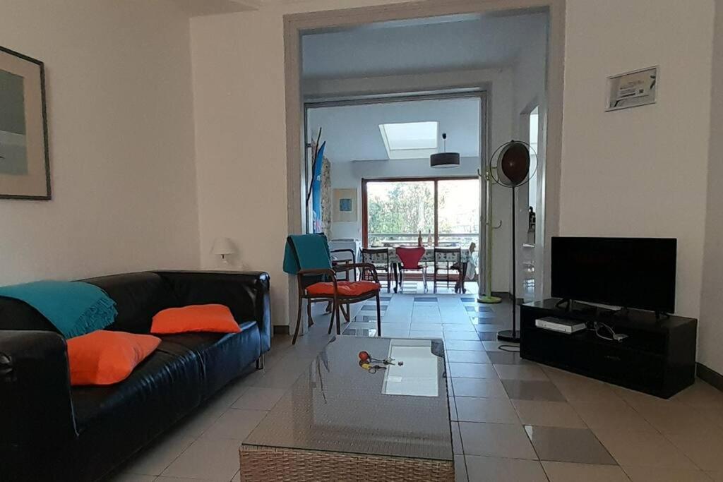 a living room with a couch and a television at Grande maison proche mer, centre Wimereux in Wimereux