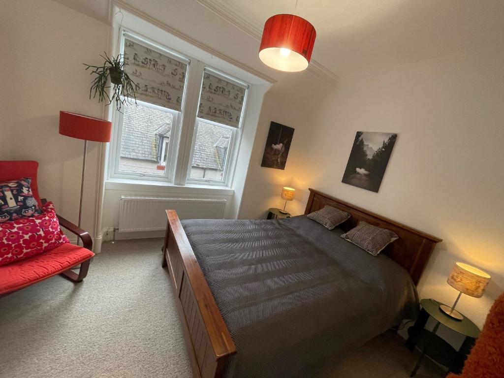 um quarto com uma cama e uma cadeira vermelha em Glen Ness Apartment in tranquil area of city centre em Inverness