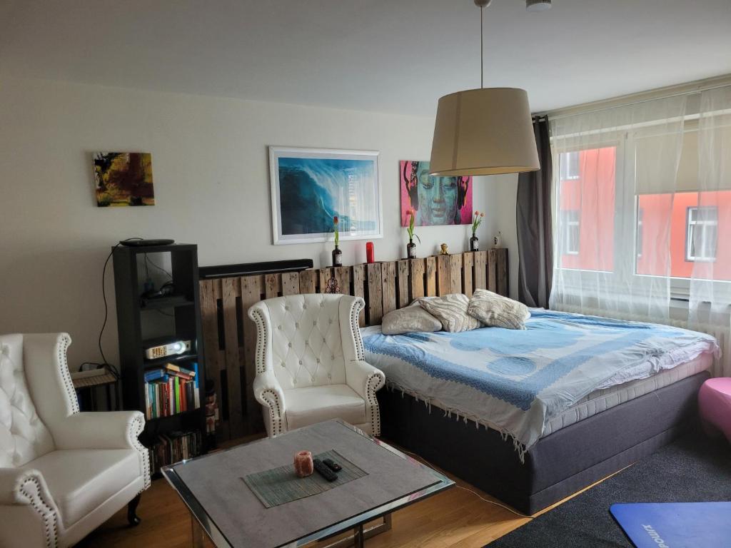 a bedroom with a bed and a chair and a table at 1 Zimmer App in Köln Ehrenfeld in Cologne