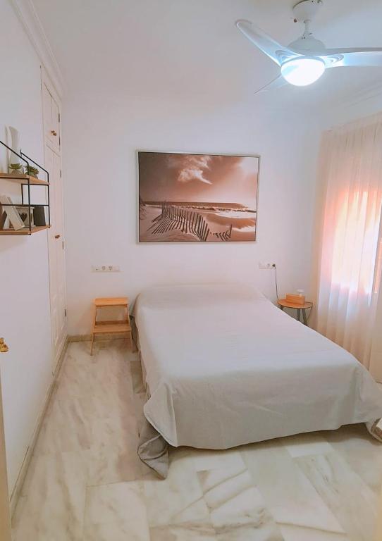 ein weißes Schlafzimmer mit einem Bett und einem Gemälde an der Wand in der Unterkunft Apartamento a 2 minutos de la playa y centro in Fuengirola