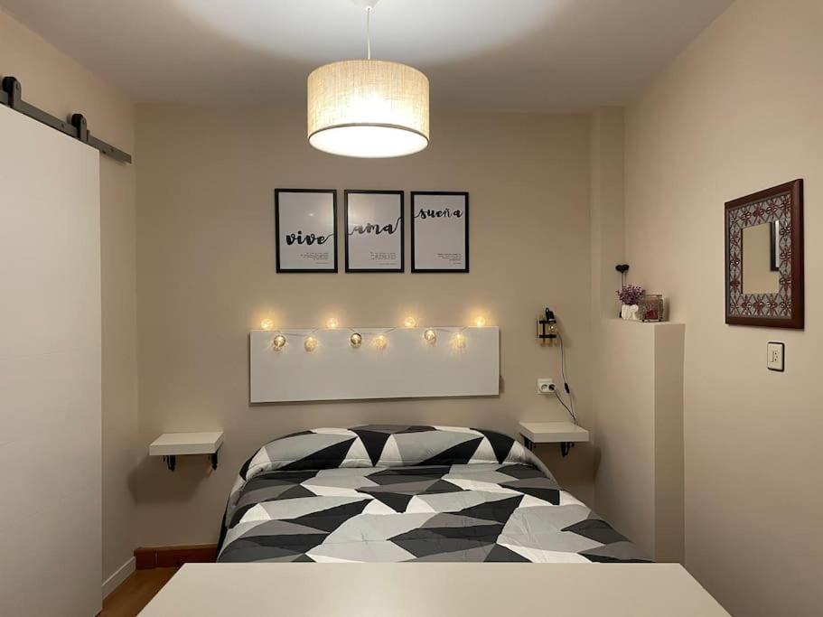 a bedroom with a black and white bed and a light at Habitación con encanto in Granada