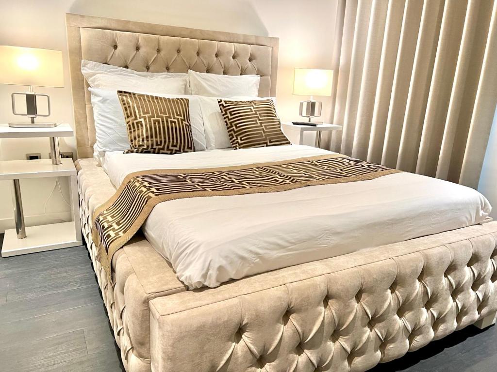 a bedroom with a large bed with white sheets and gold pillows at Staycity One Bedroom Luxury Apartment in London