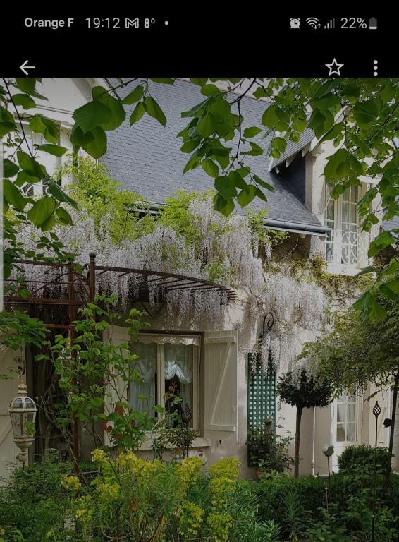 une maison avec des vignes blanches sur son côté dans l'établissement Chambres d'hôtes Jardin D'ivoire, à Saint-Gervais-la-Forêt