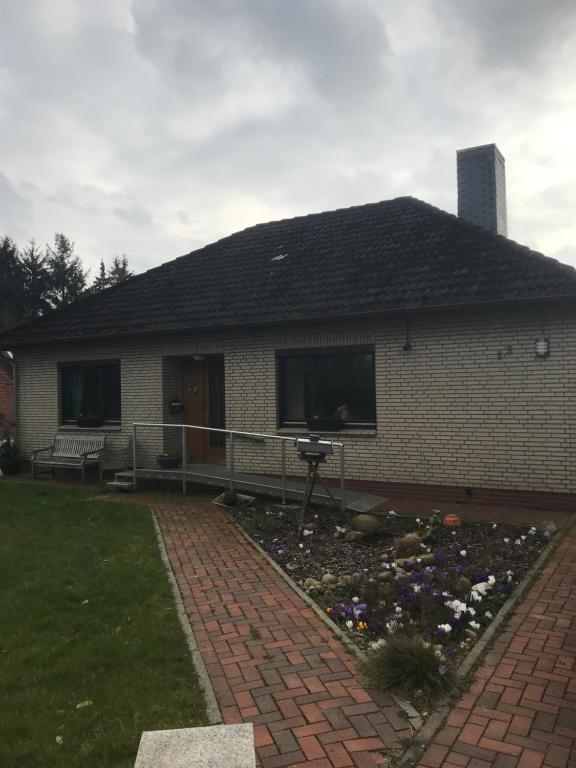 uma casa com um quintal de tijolos com um canteiro de flores em Ferienhaus am Heringskoop em Nordleda