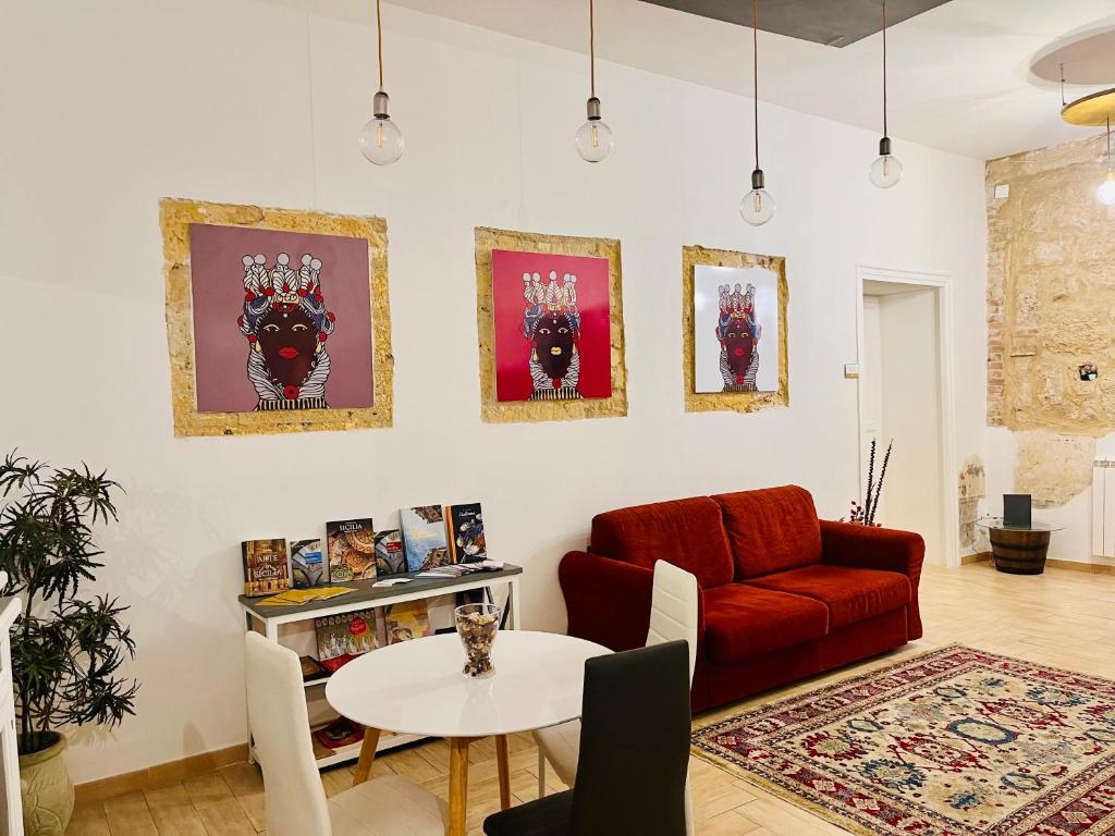 un soggiorno con divano rosso e tavolo di Palazzo delle Logge a Palermo