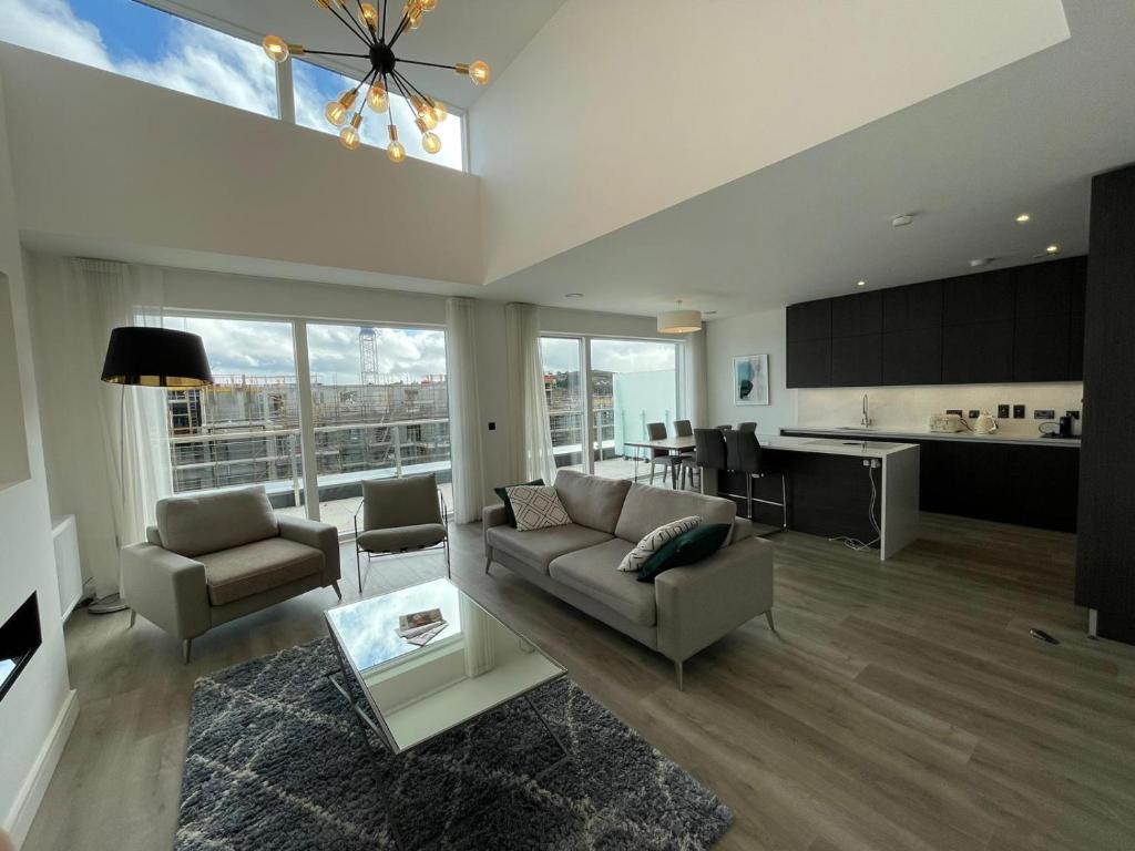 un soggiorno con divano e sedie e una cucina di Greystones Marina View Penthouse a Greystones