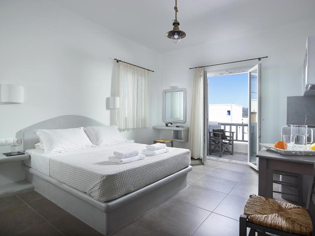 a white bedroom with a bed and a balcony at Garifalakis Comfort Rooms in Pollonia