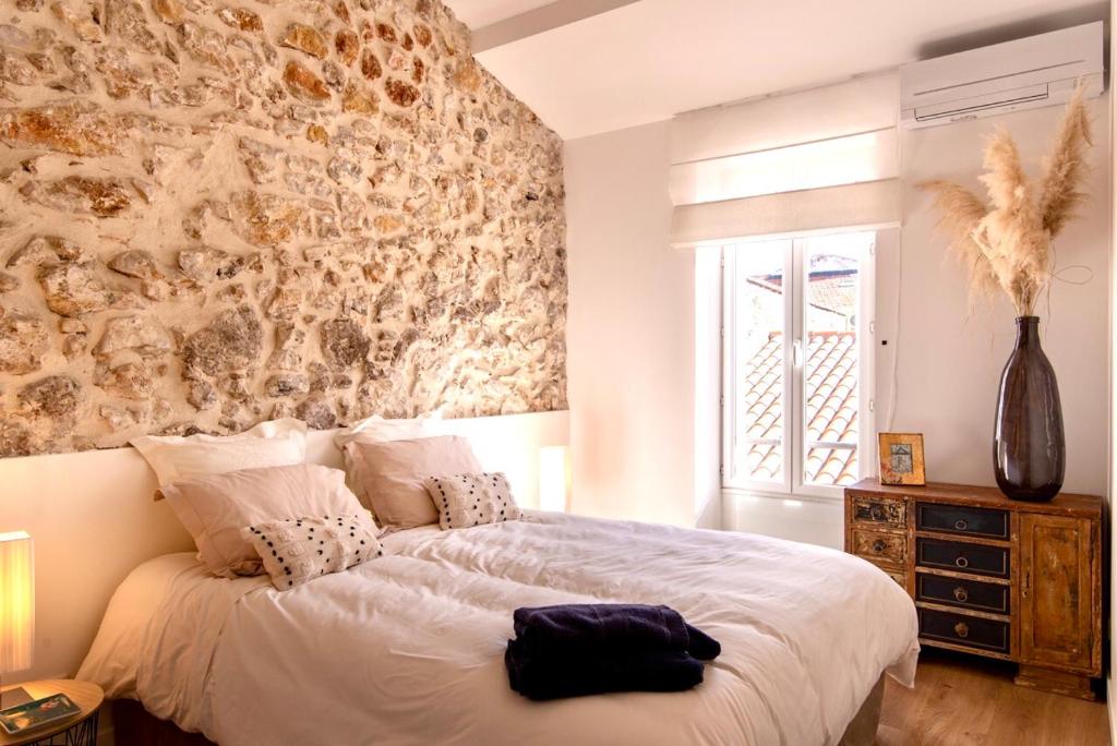 a bedroom with a large bed with a stone wall at L appartement de Manon, centre historique du vieil Antibes in Antibes