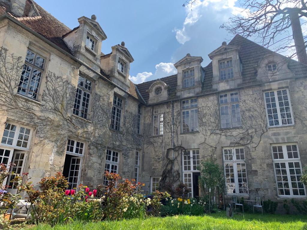 an old stone building with windows and flowers at La Maison Saint Joseph in Crépy-en-Valois