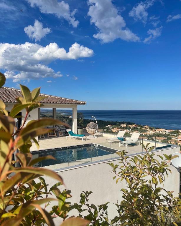 une piscine avec des chaises et l'océan en arrière-plan dans l'établissement Villa Mare d'argentu La solenzara, à Sari-Solenzara